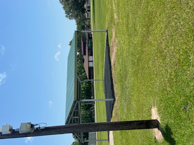 New carport installation under construction with workers on roof.
